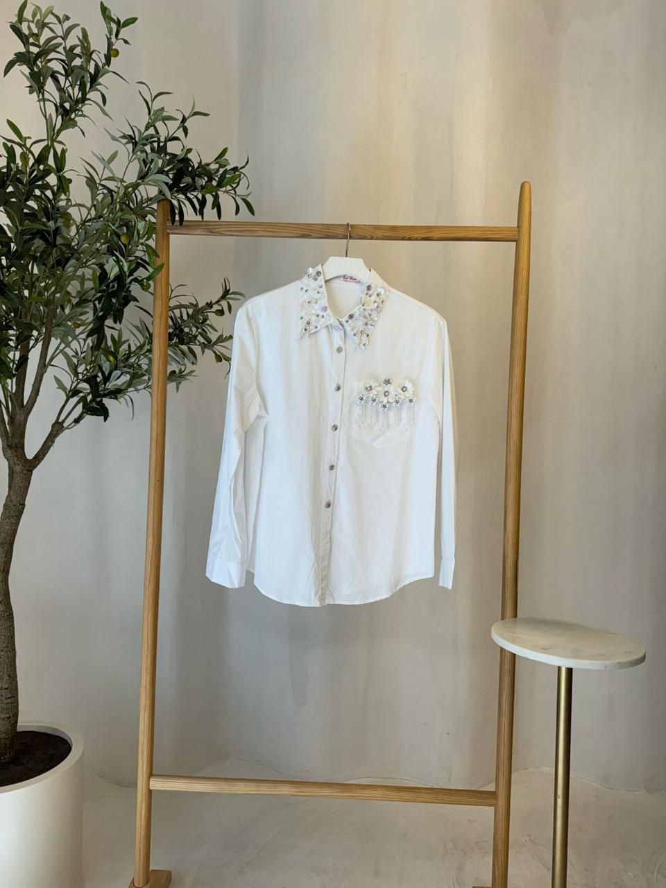 CAMISA  BLANCA MANGA LARGA CON APLICACIÓN EN FLORES Y PIEDRAS EN CUELLO Y BOLSA FRONTAL